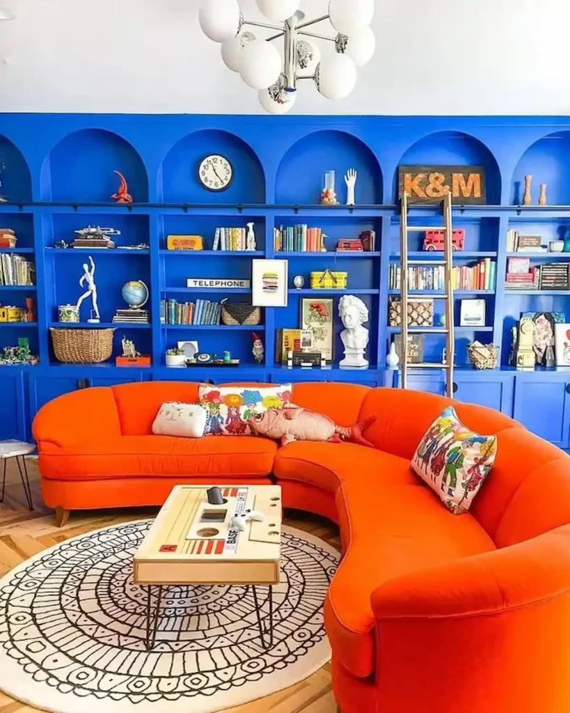 Photo d'un salon, avec un grand canapé d'angle de couleur orange vif, un mur bibliothéque bleu électrique et une décoration rétro et coloré 