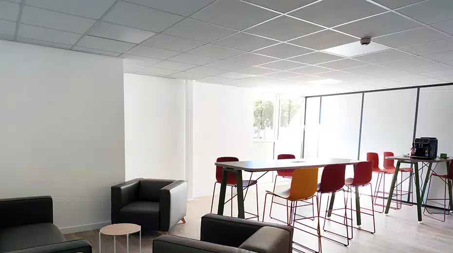 Photo d'un espace de coworking, fauteuils, tables et chaises hautes, machine à café