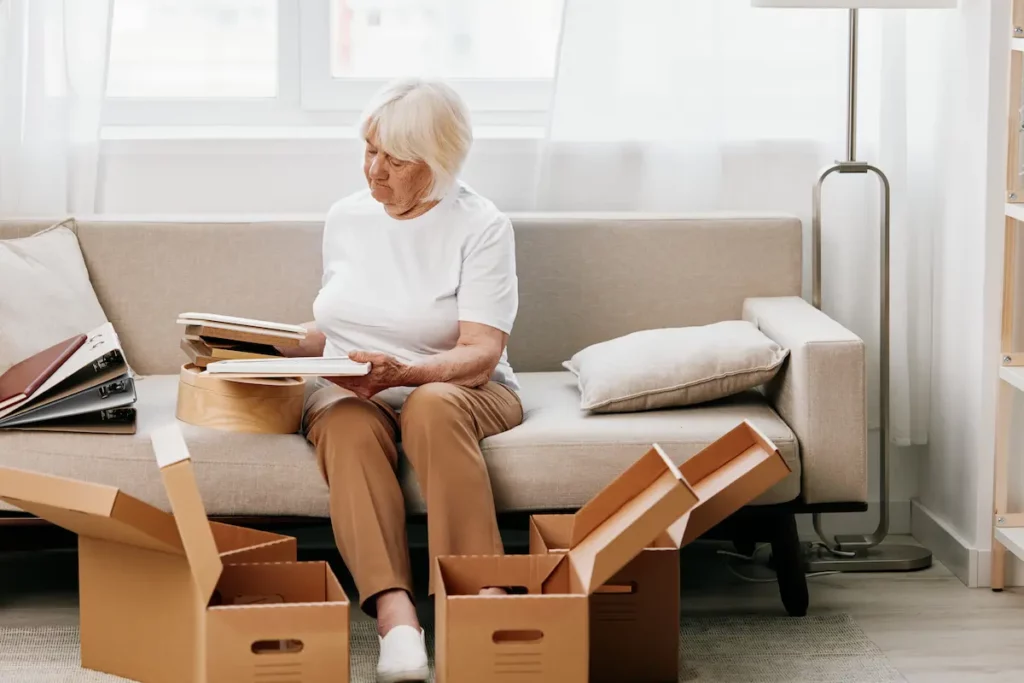 Senior assise sur un canapé entrain de faire ses cartons de déménagement.