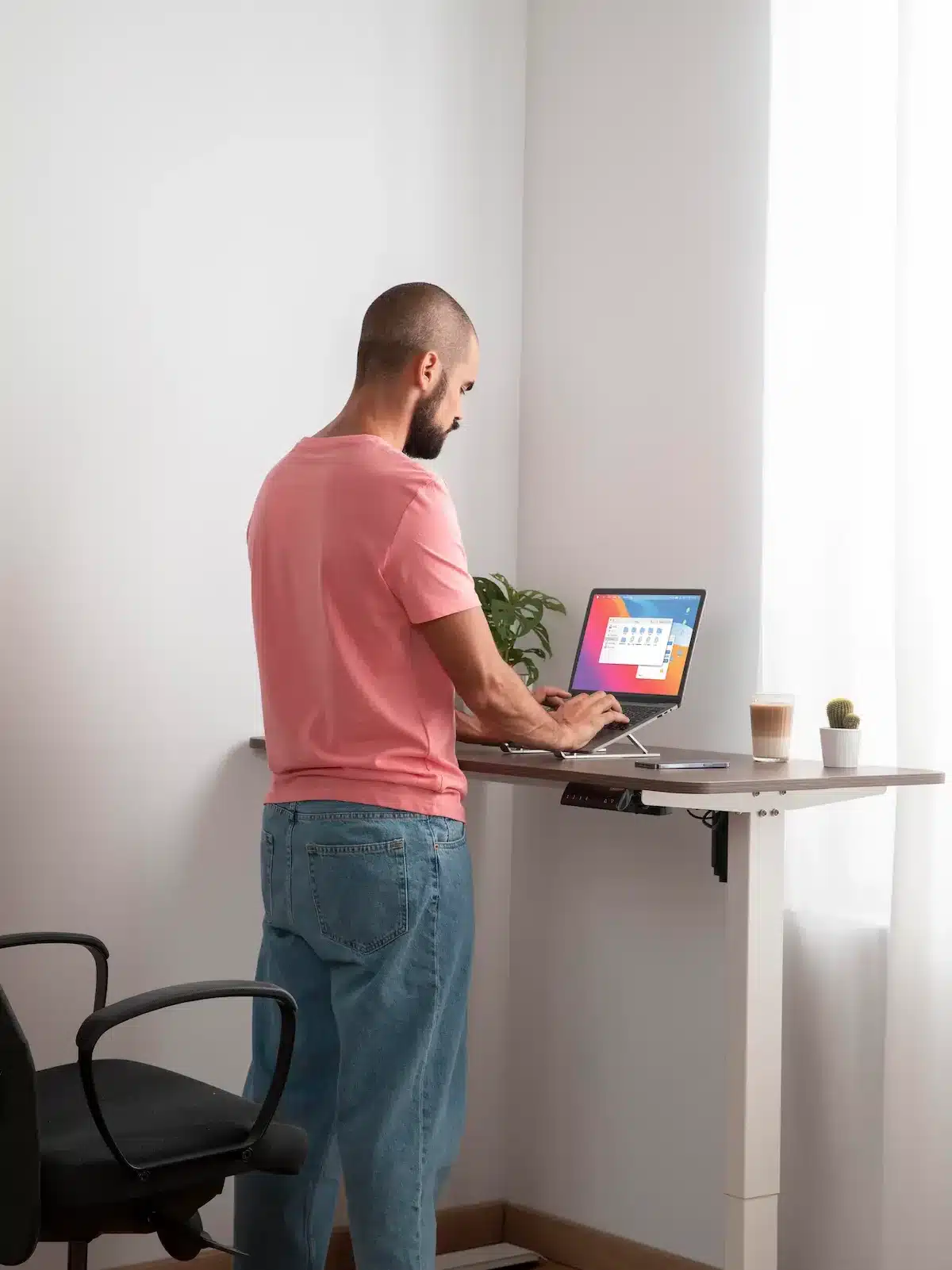 Homme en train de travailler debout face un bureau ergonomique. 