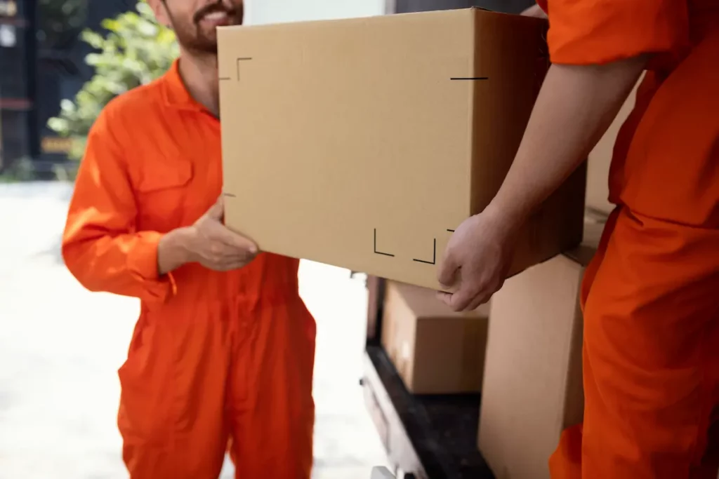 Entreprise de déménagement, deux déménageur chargent un carton dans un camion.