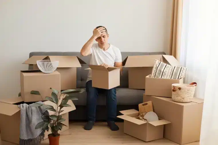 Homme entrain de aire ses cratons de déménagement sur son canapé entouré de carton