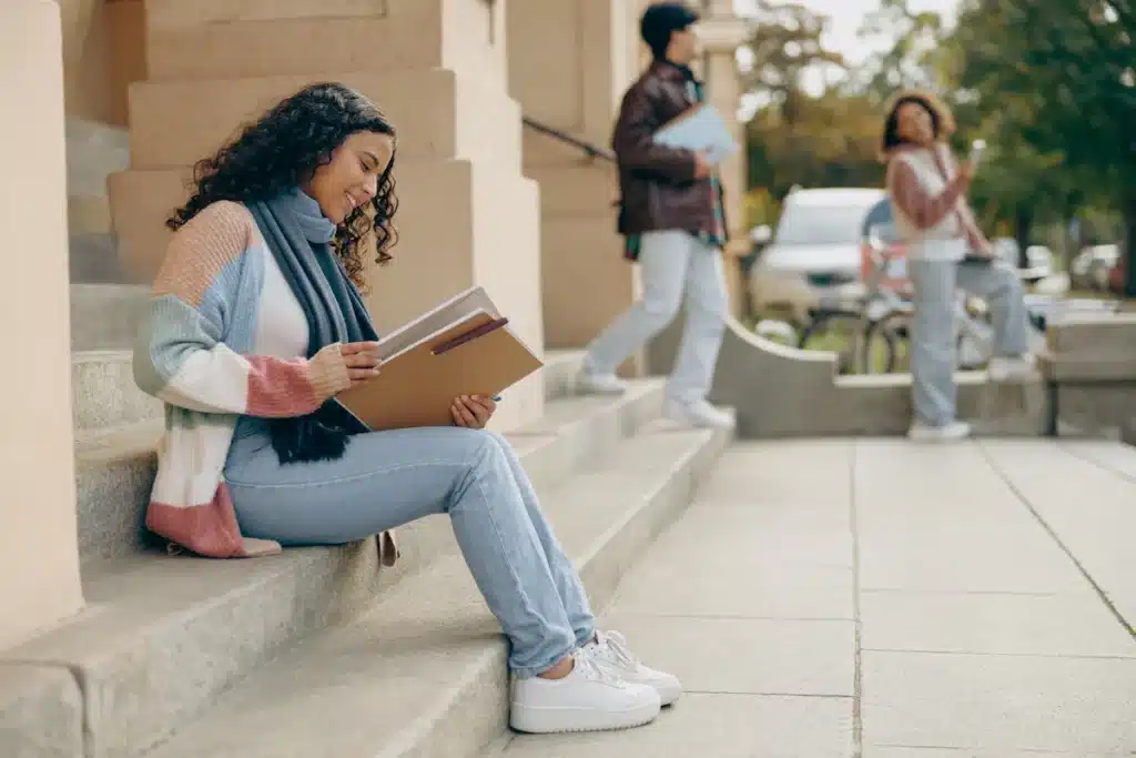 Étudiante assise sur des marches avec des documents en mains. 