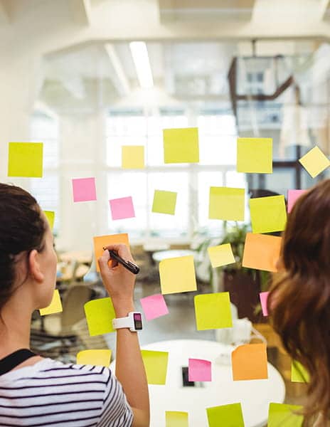 Femmes écrivent sur des post-it en entreprise. Planification