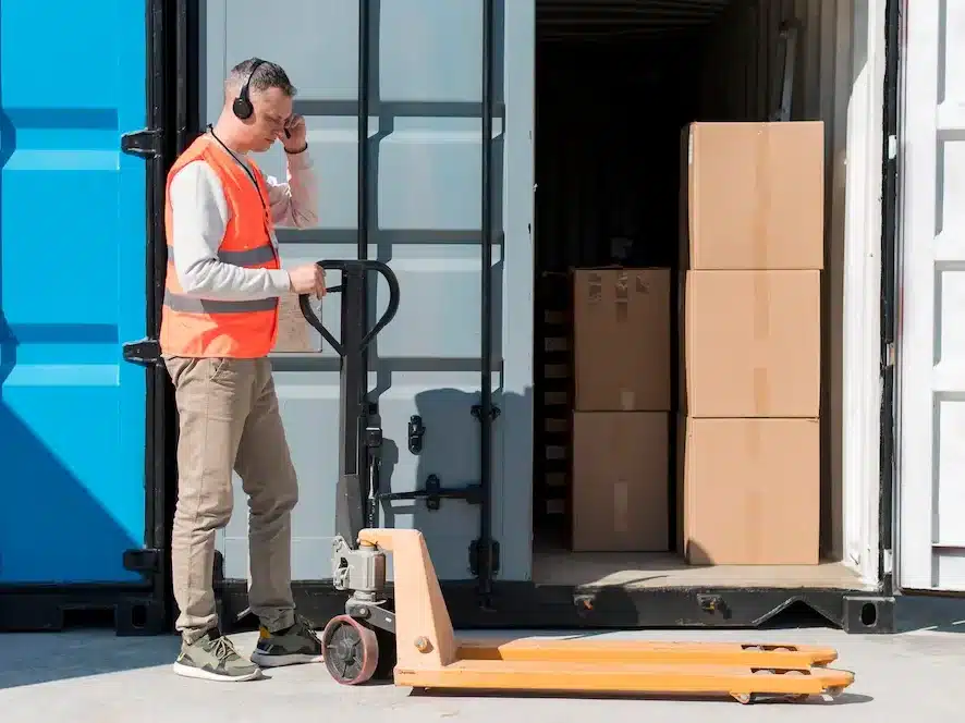 Homme déchargeant le contenu d'un transpalette dans un container de stockage