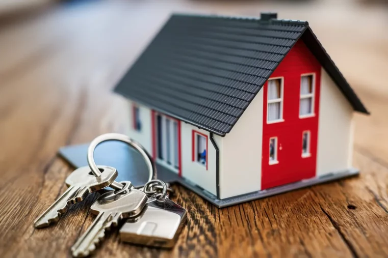 Maquette d'une maison en miniature, avec un trousseau de clés à côté, pour illustrer la vente ou la location d'un bien.