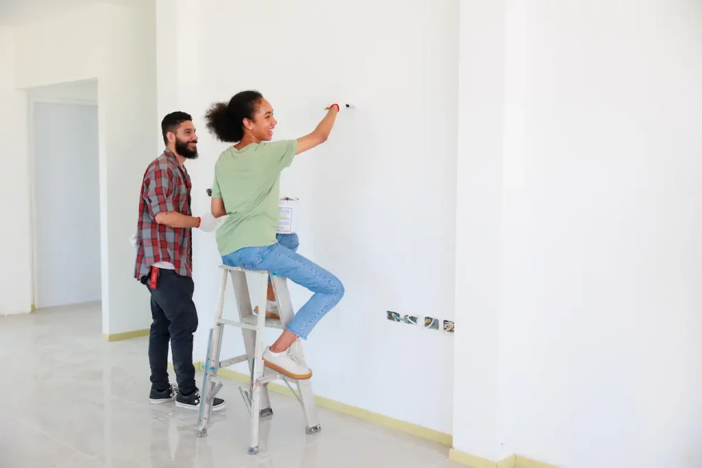 Un homme et une femme entrain de repeindre les murs d'un appartement à louer ou à vendre.