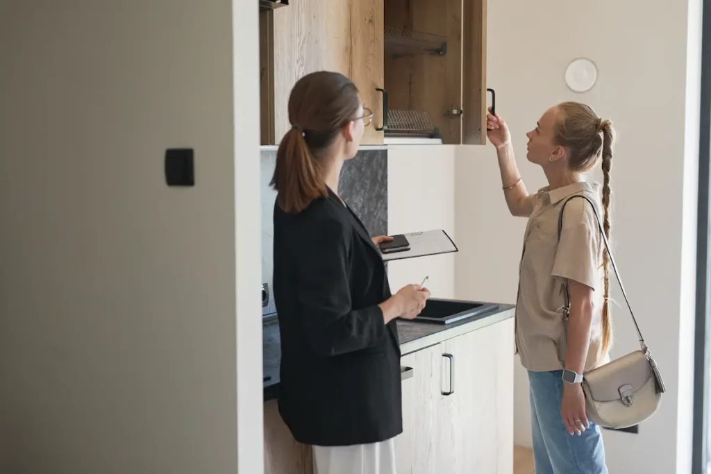 Visite d'un appartement à louer, deux femmes, un agent immobilier et une locataire entrain de visiter la cuisine. 