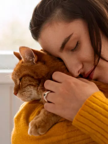 Femme tenant son chat dans ses bras en douceur. Elle le rassure avant un déménagement