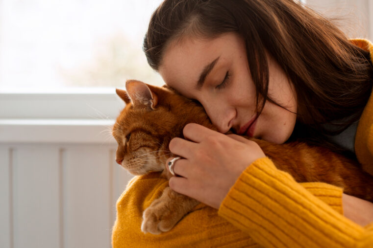 Femme tenant son chat dans ses bras en douceur. Elle le rassure avant un déménagement