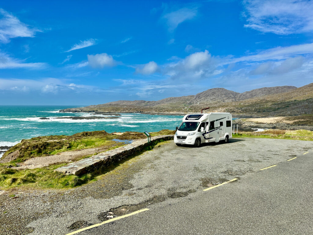 Camping-car stationné en bord de mer, face à une eau turquoise éclatante.