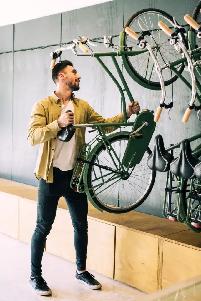 Photo d'une personne qui accroche son vélo sur un suport mural