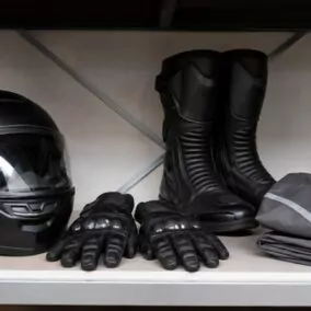 Casque, gants, bottes et blouson de moto rangés sur une étagère