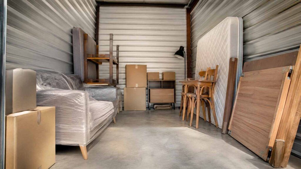 Intérieur d’un box de stockage avec canapé emballé, matelas, table et cartons