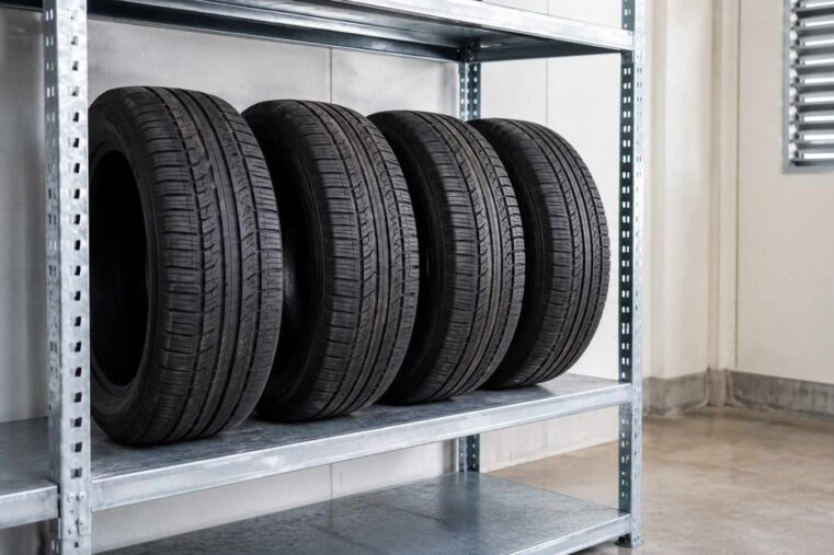 Quatre pneus rangés debout sur une étagère métallique dans un local sec et ventilé
